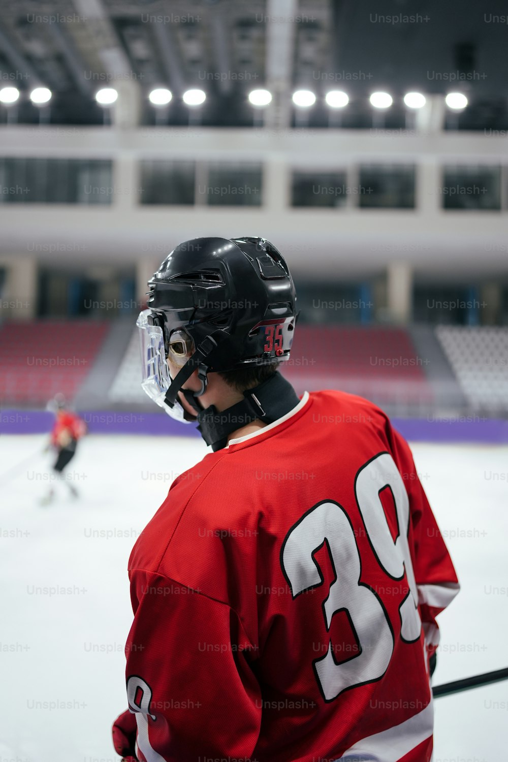 a hockey player wearing a red jersey and helmet