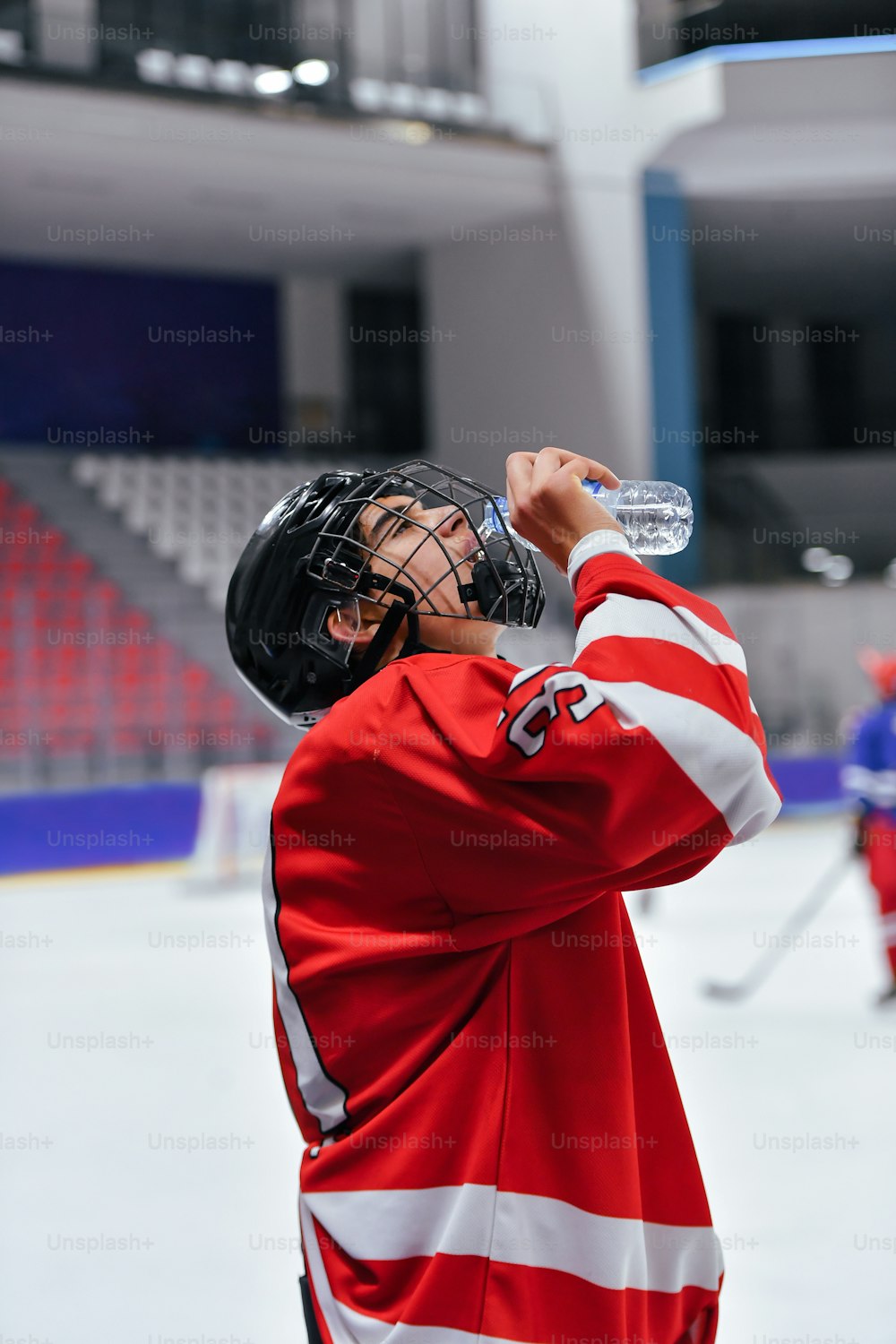 Ein Eishockeyspieler trinkt Wasser aus einer Flasche