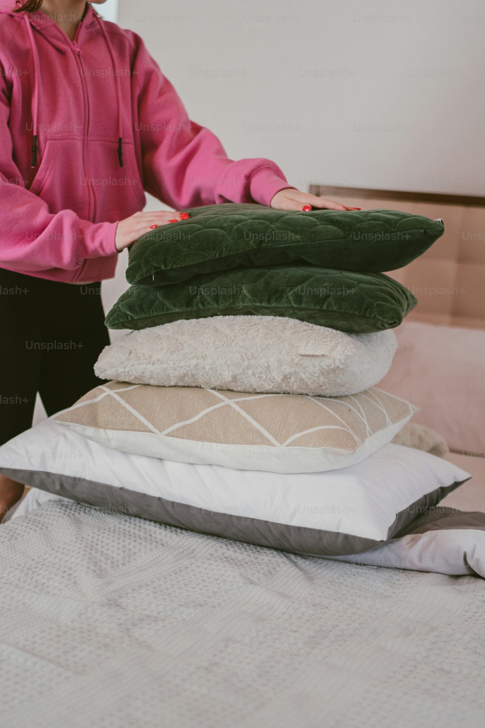 Una mujer de pie junto a una pila de almohadas