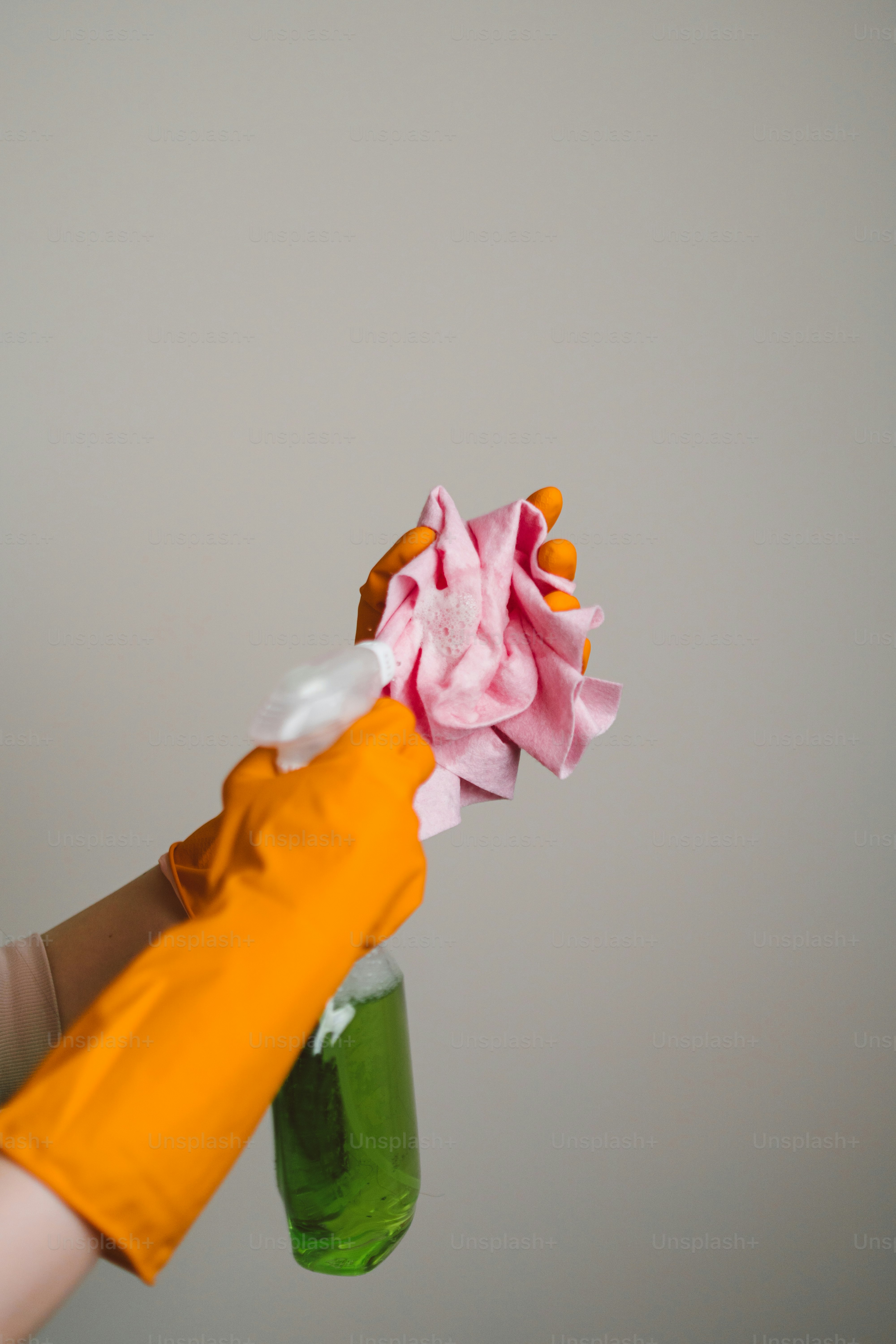 A person wearing orange gloves holding a bottle of cleaner photo ...