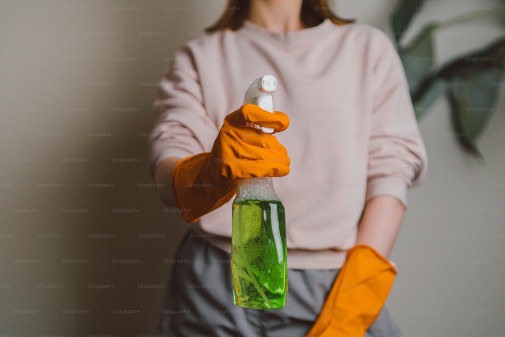 a person in orange gloves holding a green bottle