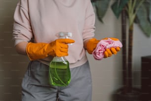 une personne portant des gants orange tenant une bouteille de nettoyant