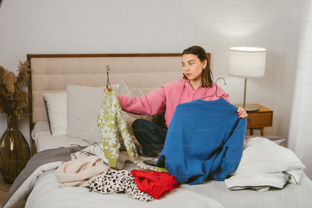 a woman sitting on a bed with clothes on a rack