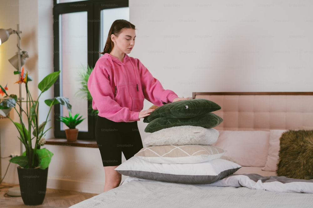 a woman standing next to a pile of pillows