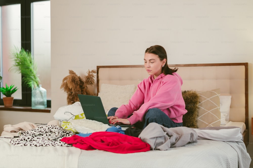 a woman sitting on a bed with a laptop