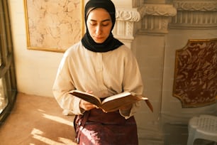 a woman in a hijab is reading a book