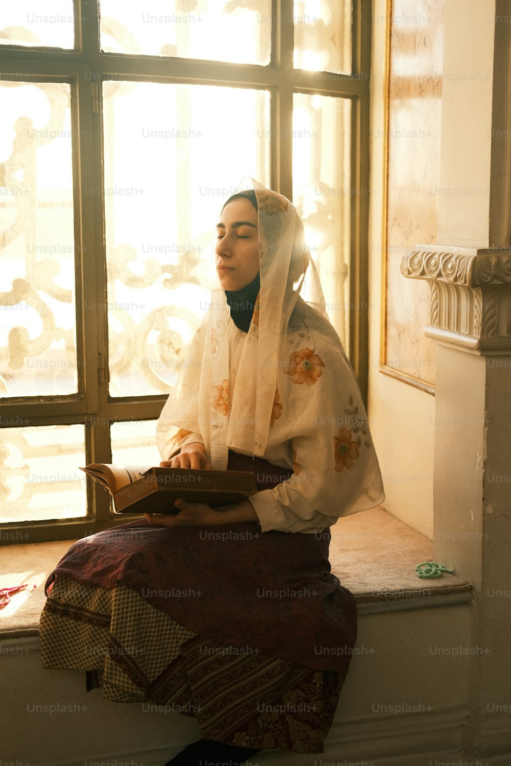 Una donna seduta sul davanzale di una finestra che legge un libro