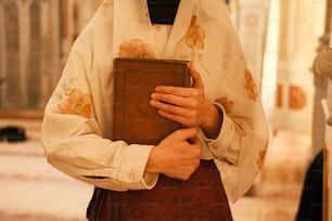 eine Person in einem Priesteroutfit, die ein Buch hält