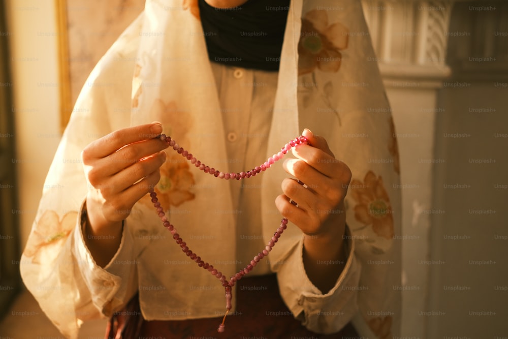 a woman holding a string of beads in her hands
