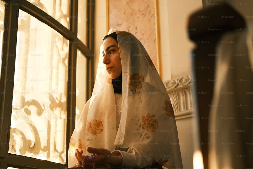 Une femme en voile blanc regardant par une fenêtre