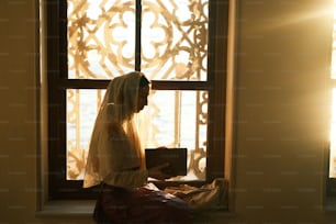 Eine Frau sitzt auf einer Fensterbank und liest ein Buch