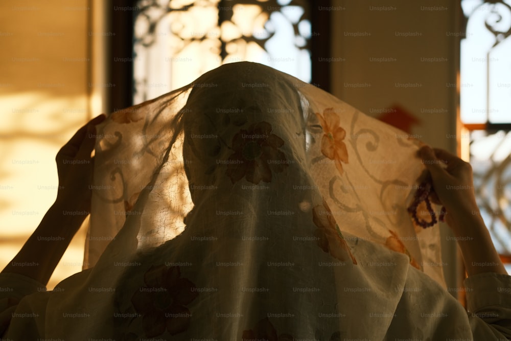 a woman is covering her face with a sheer cloth