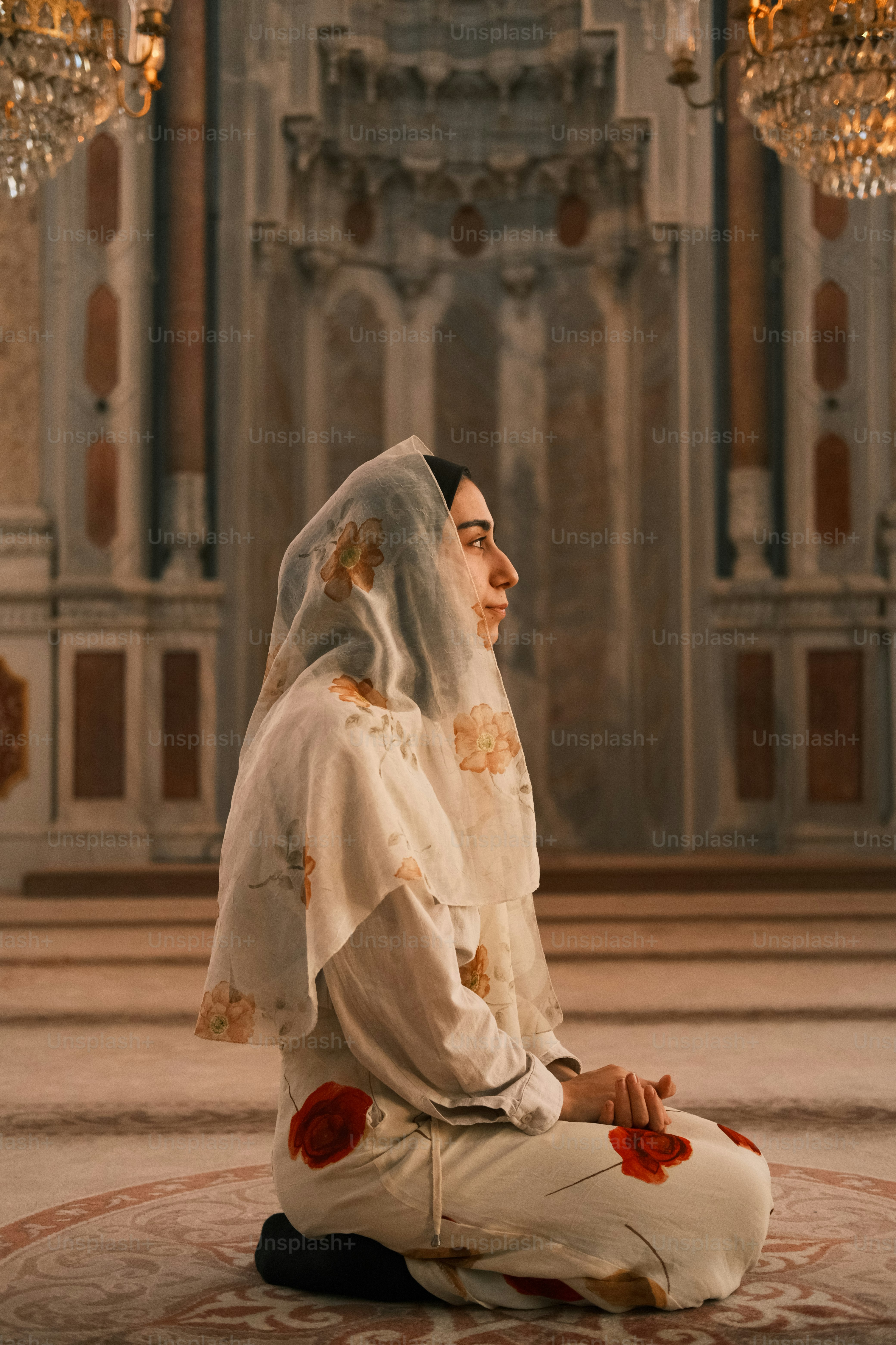 Eine Frau sitzt auf dem Boden vor einem Kronleuchter