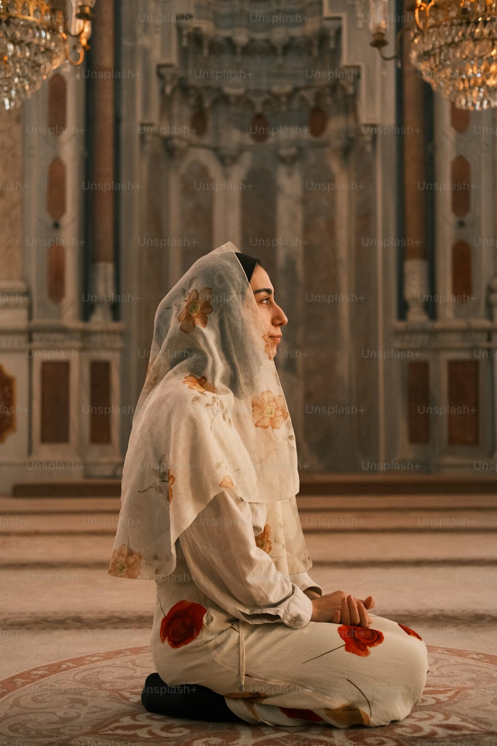 Eine Frau sitzt auf dem Boden vor einem Kronleuchter