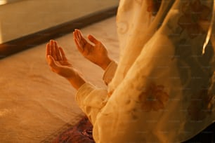 a woman sitting on the floor with her hands in the air