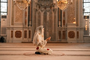 a bride kneeling on the floor in front of a chandelier