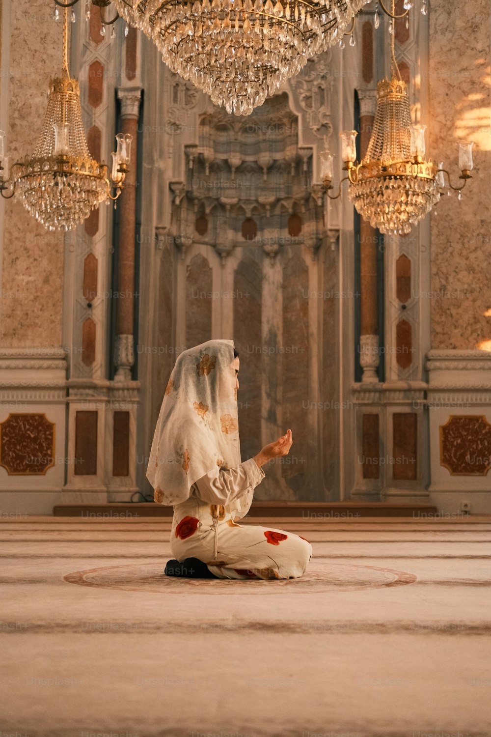 하얀 베일을 쓴 여자가 샹델 앞 바닥에 앉아 있다