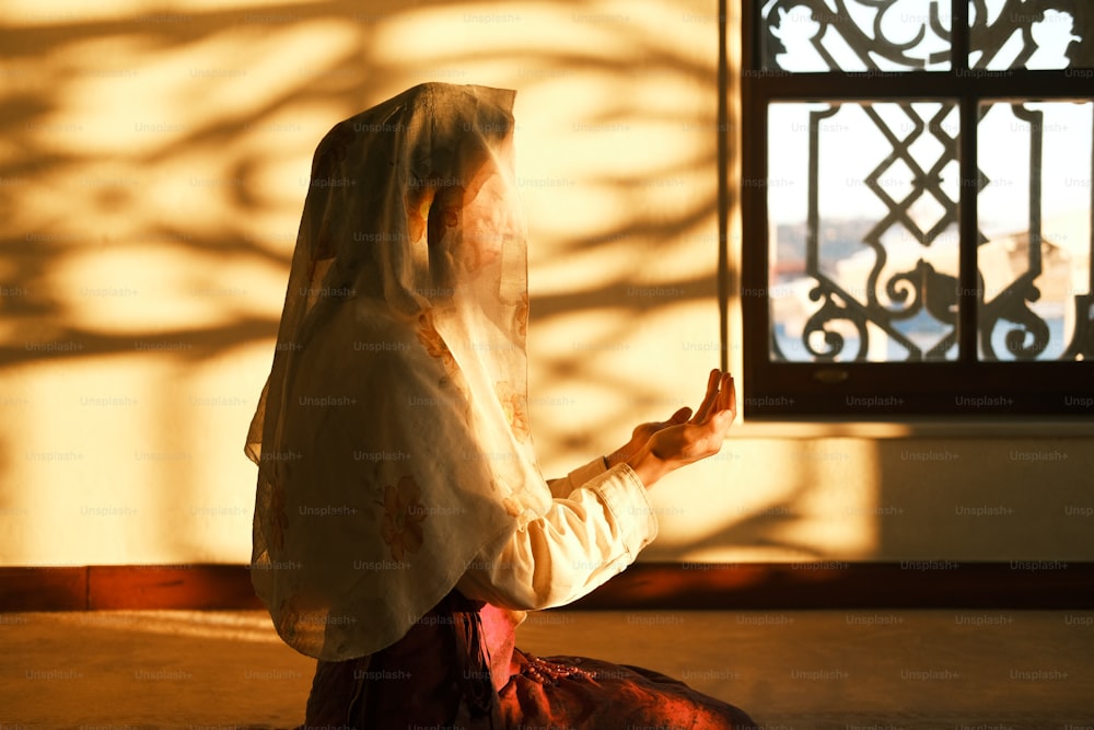 Una mujer sentada en el suelo frente a una ventana