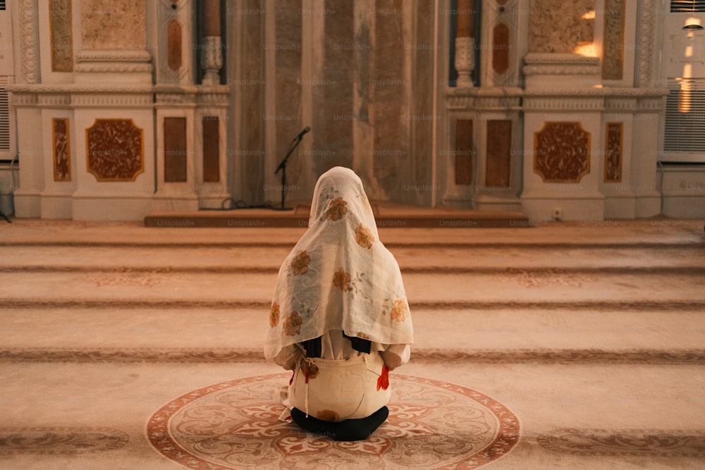 Eine Frau in weißem Schleier sitzt auf dem Boden