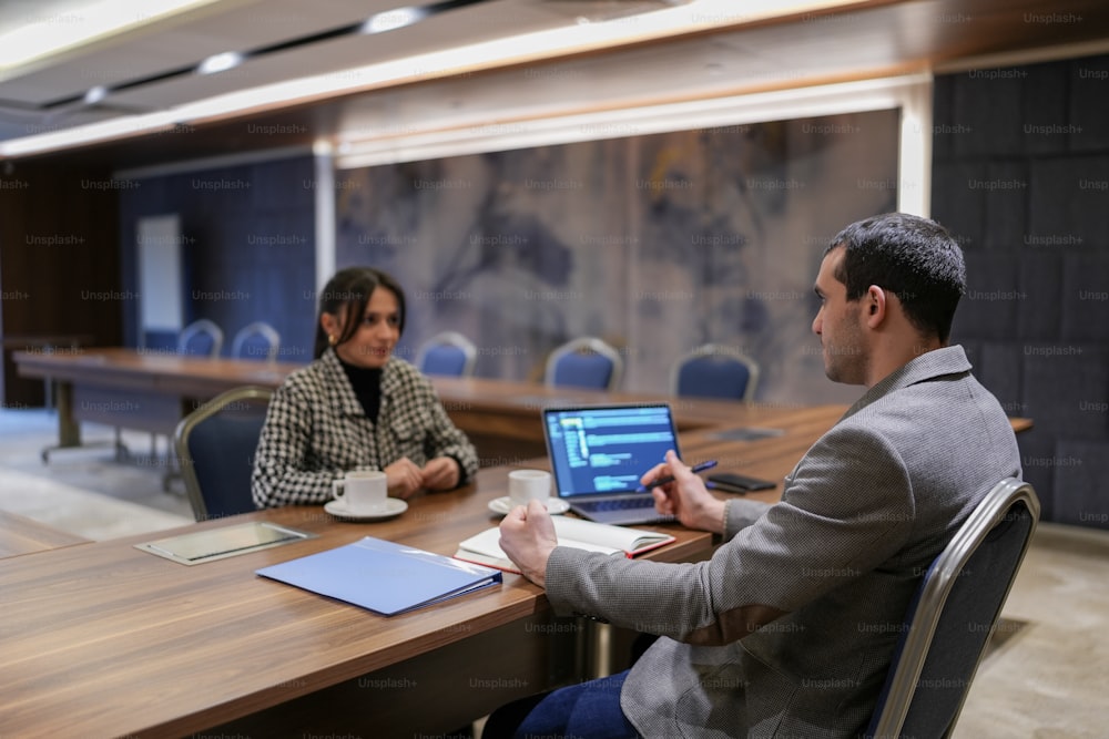 a man and a woman sitting at a table with laptops