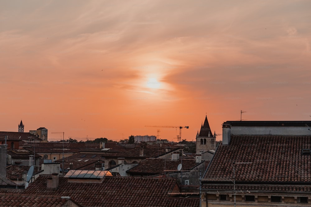 the sun is setting over the rooftops of a city