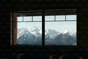 una finestra con vista su una catena montuosa innevata