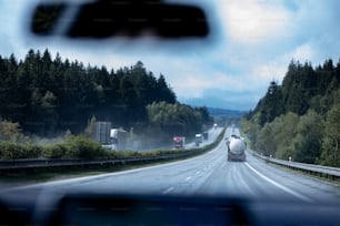 a truck driving down a road next to a forest