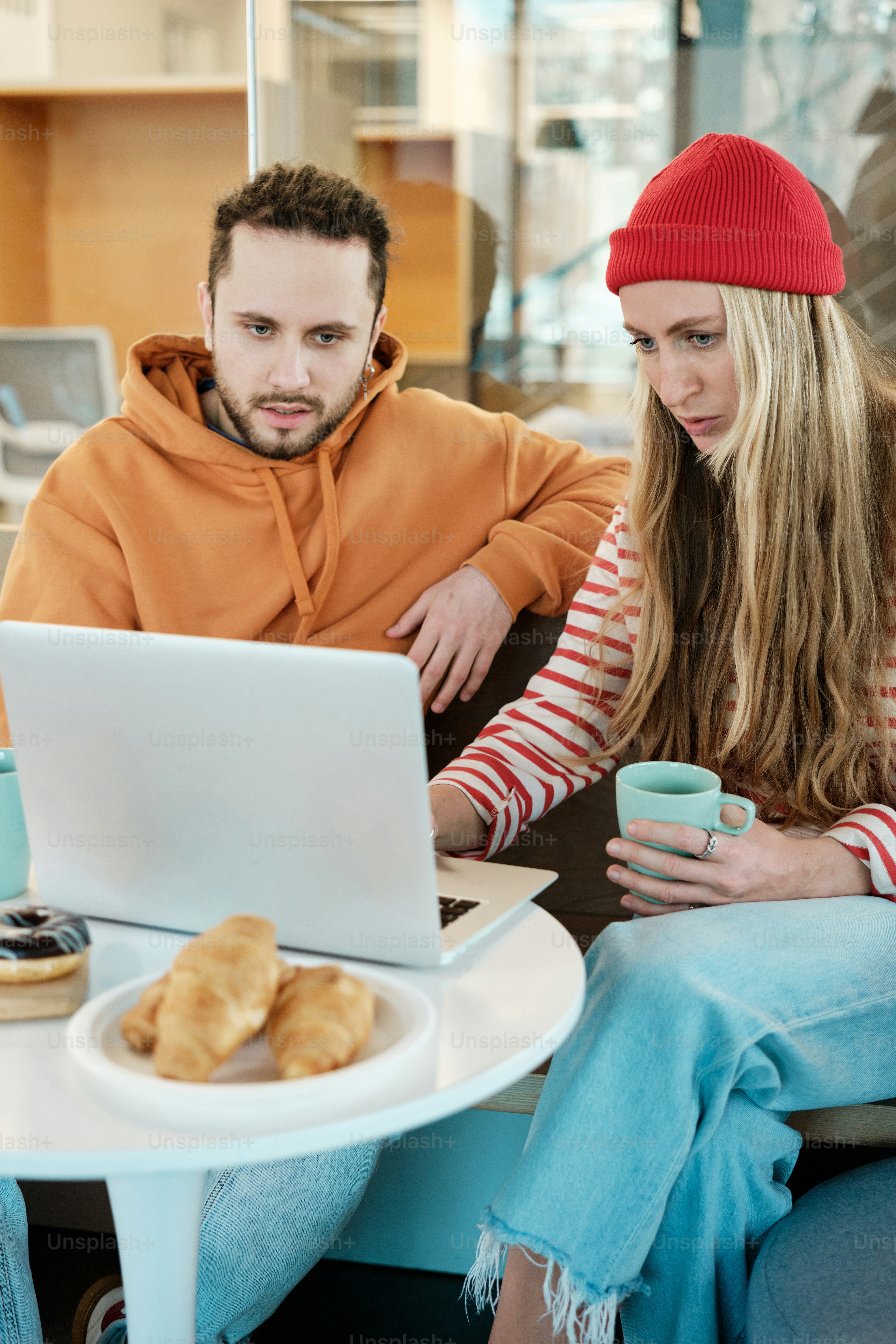 a man and woman sitting at a table looking at a laptop