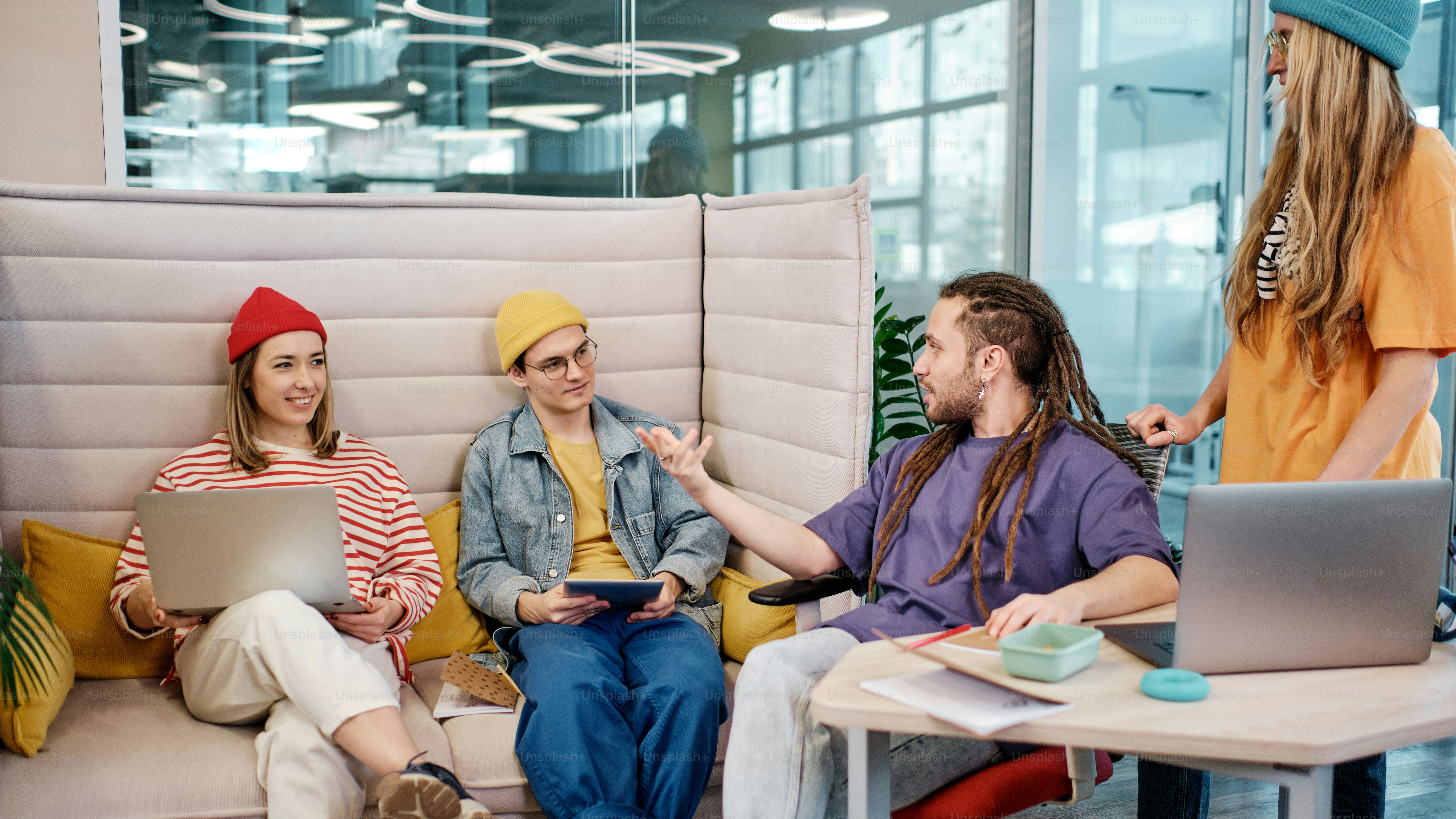 a group of people sitting on a couch with laptops