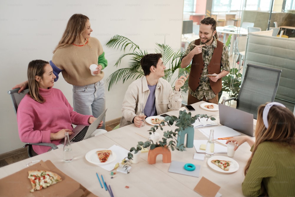 a group of people sitting around a table eating pizza