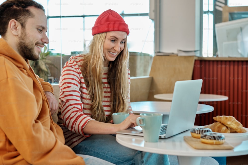 a man and a woman sitting at a table with a laptop