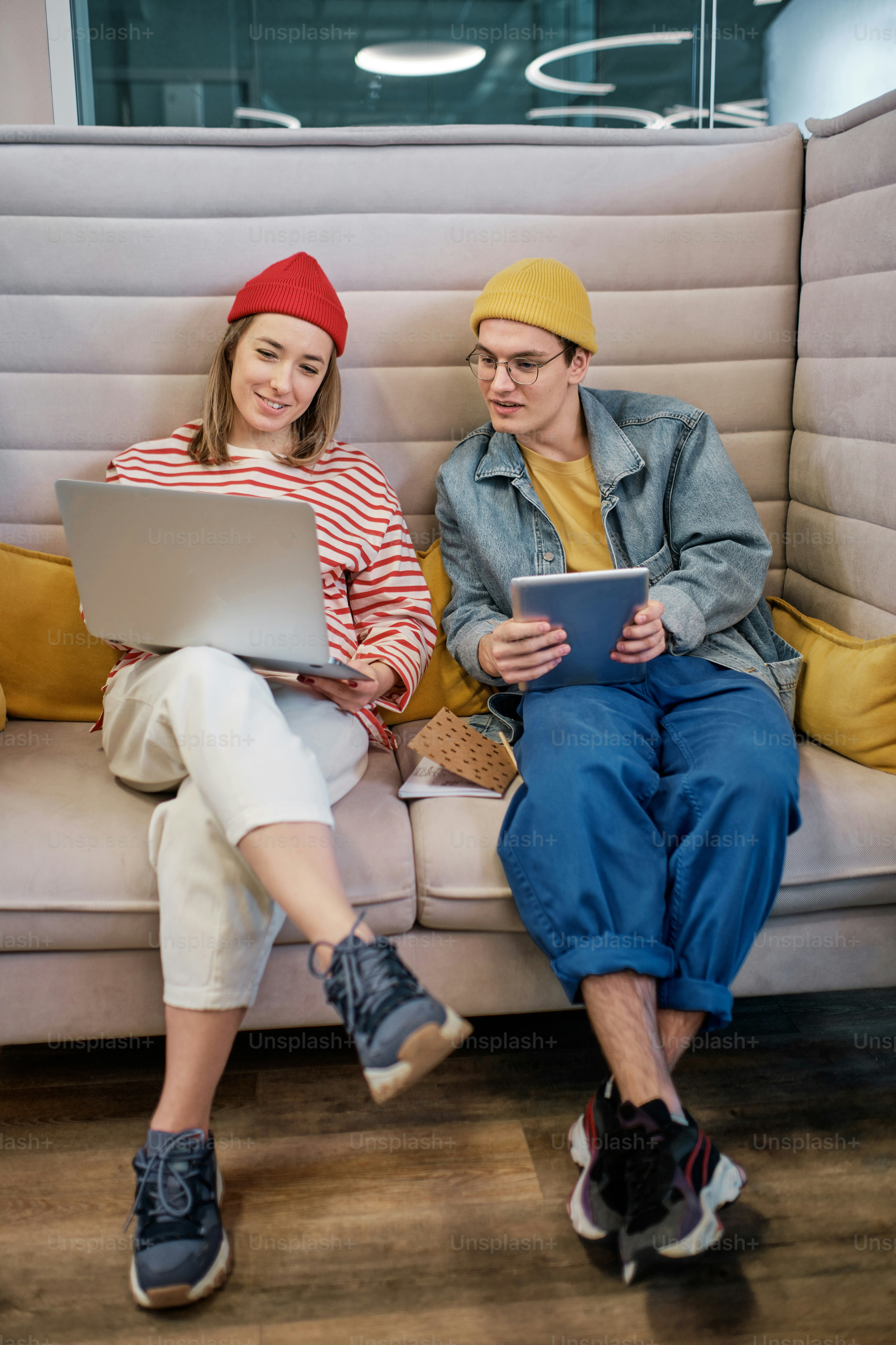 a man and a woman sitting on a couch looking at a laptop
