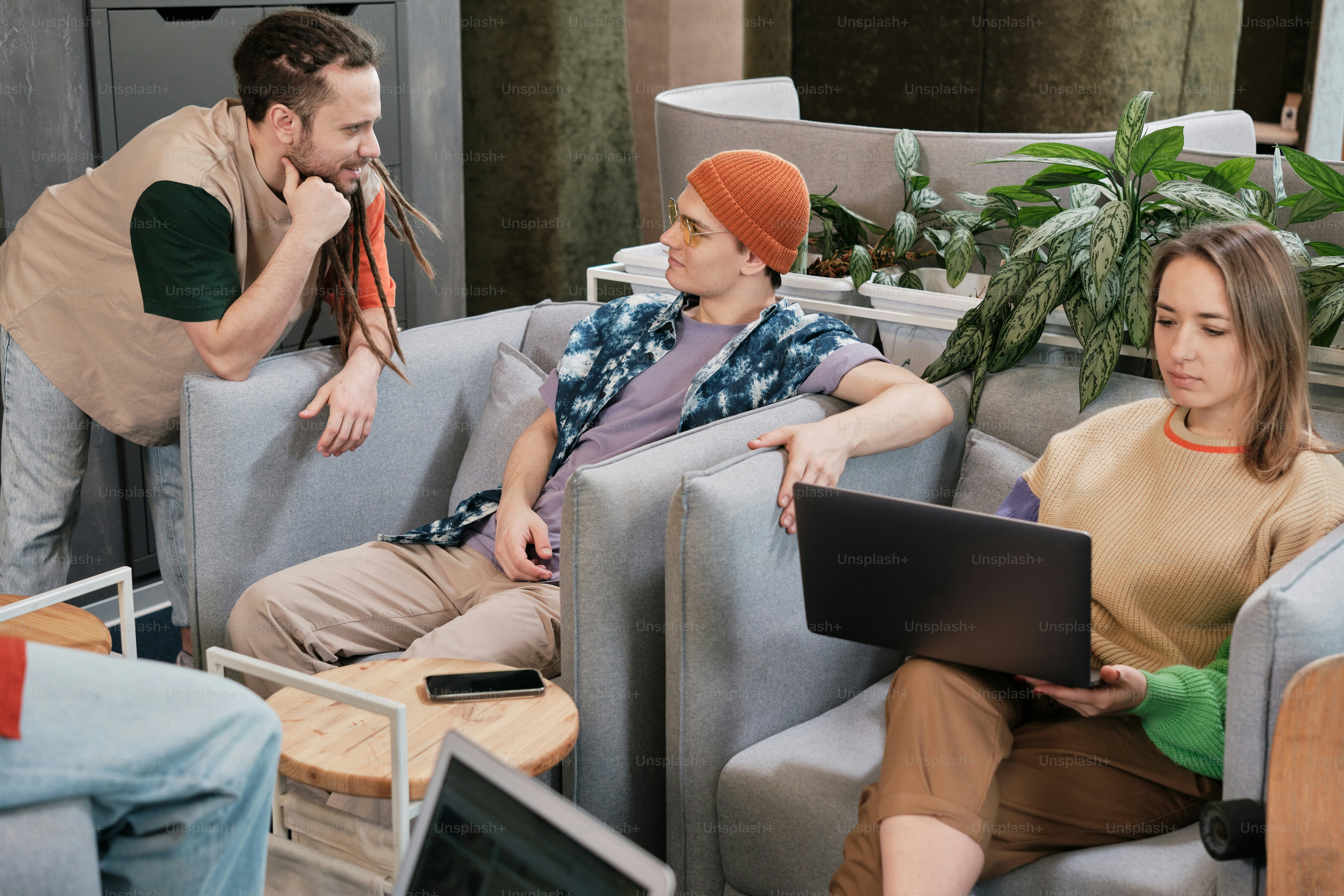 a man and a woman sitting on couches with laptops