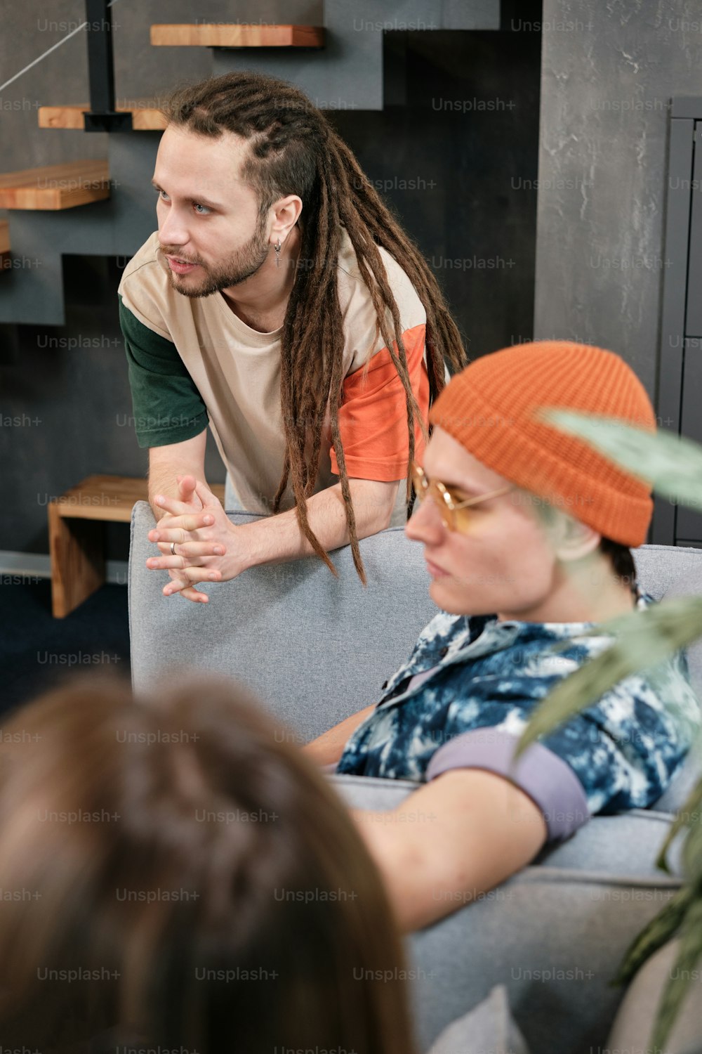 a man with dreadlocks talking to a woman on a couch