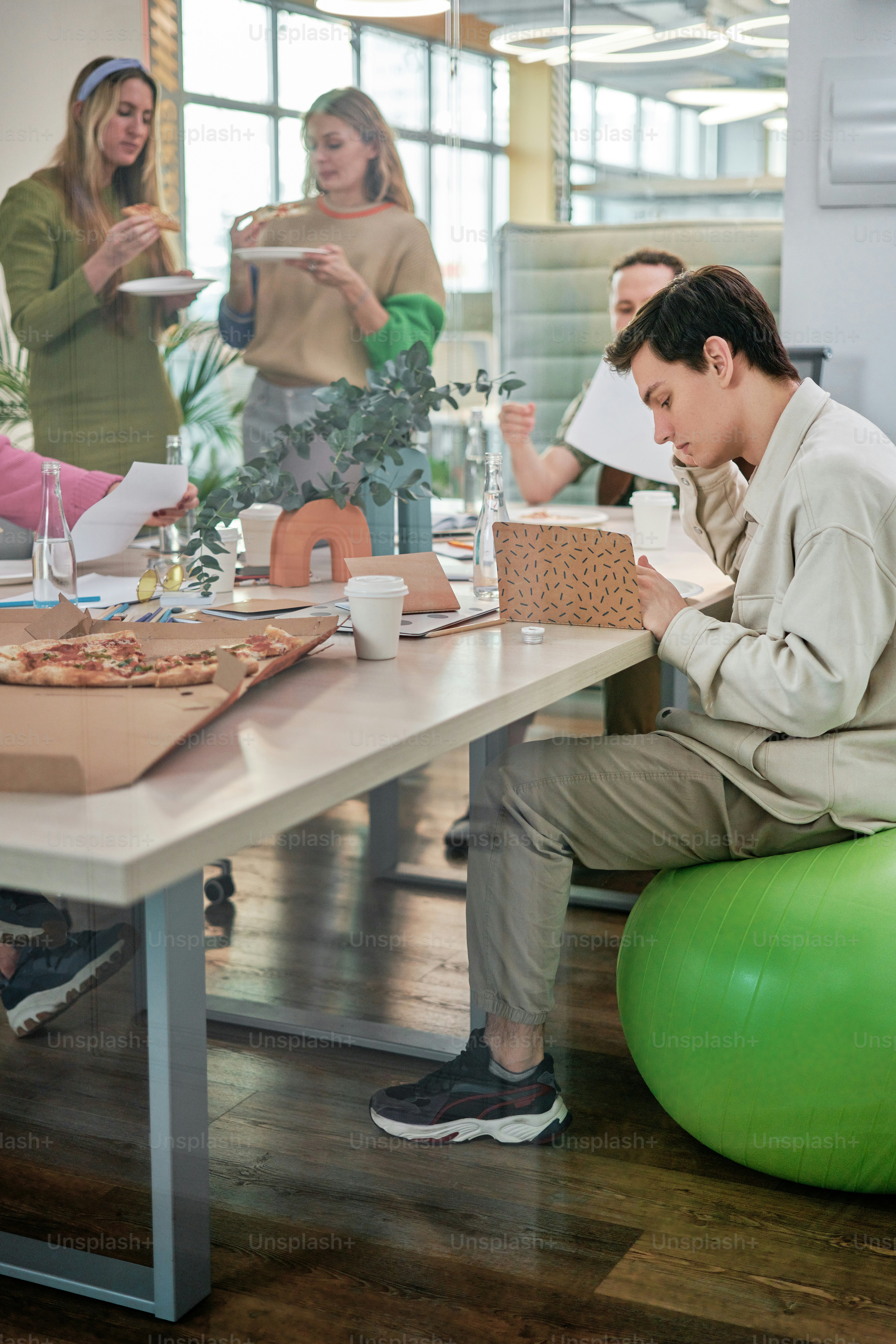 a group of people sitting around a table eating pizza