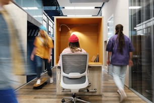 a woman in a red hat is sitting at a desk