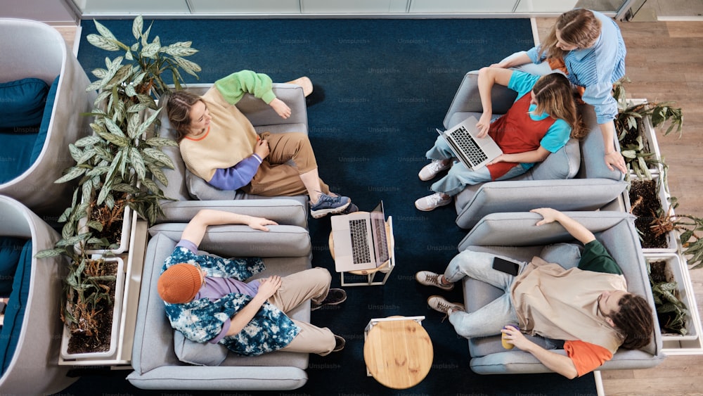 a group of people sitting on couches with laptops