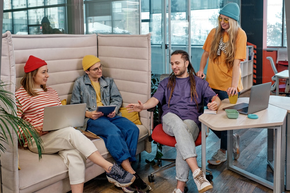 a group of people sitting around a table with laptops