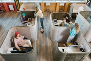 a group of people sitting in cubicles in an office