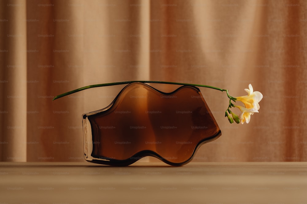 un jarrón marrón con una flor que sobresale de él
