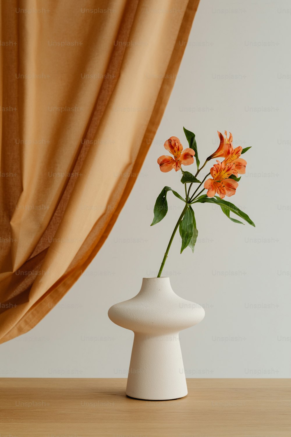 un vase blanc avec des fleurs oranges dedans