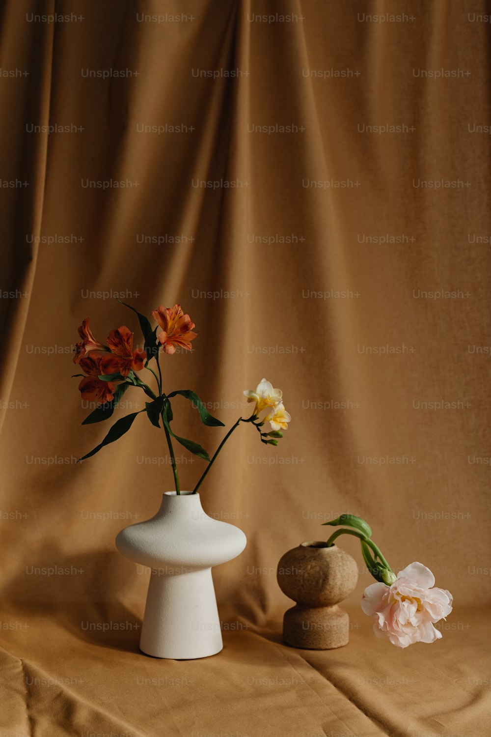 un vase blanc avec des fleurs à côté d’un rocher
