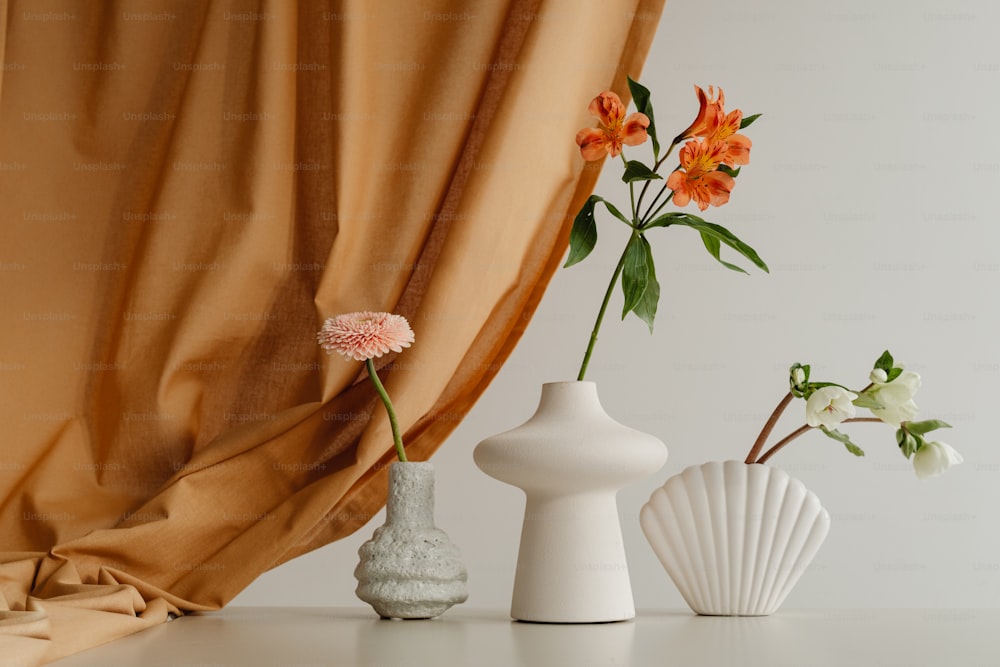 three vases with flowers in them sitting on a table
