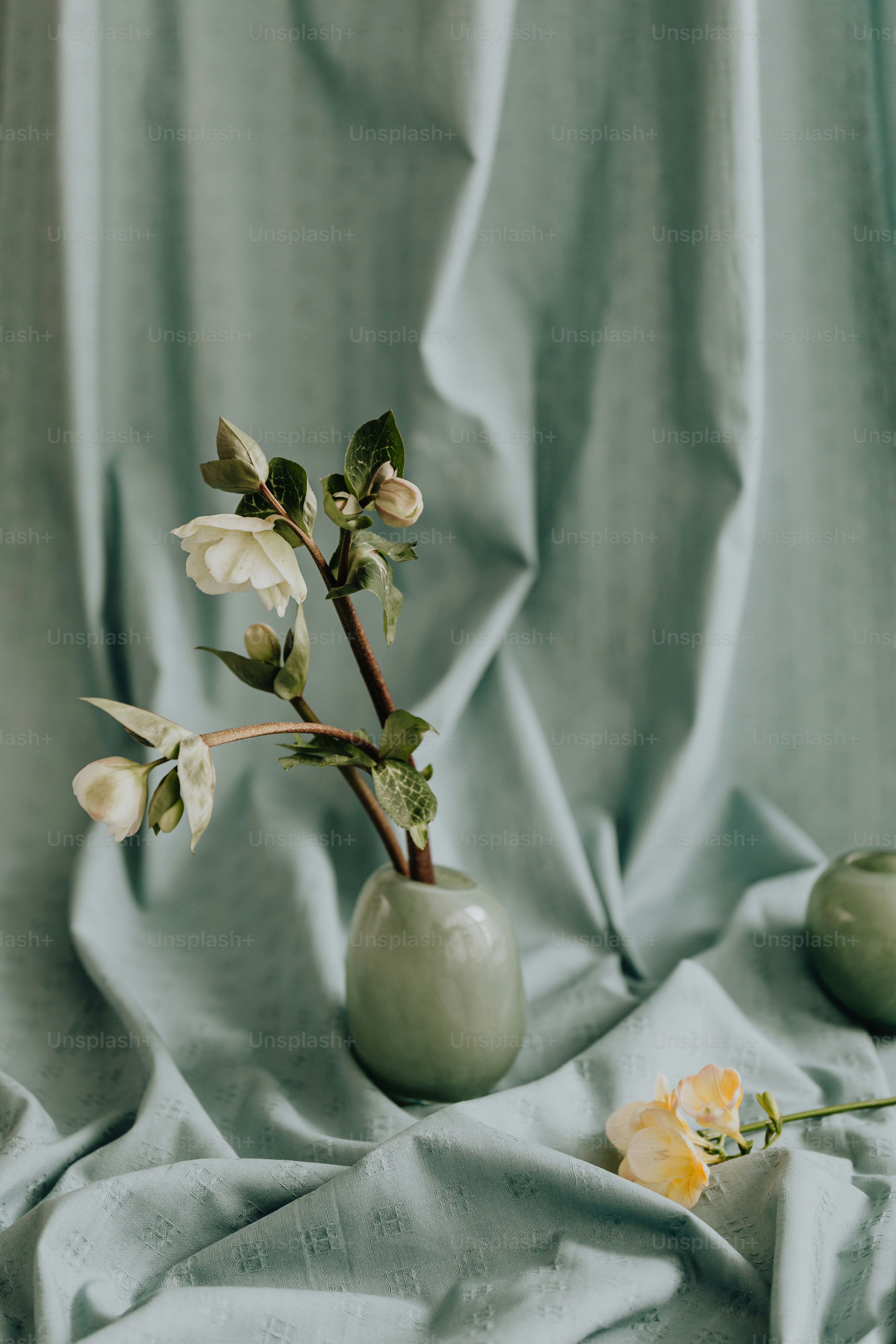 A green vase with flowers in it on a blue cloth photo Floral