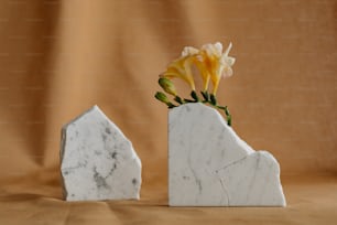 um vaso de mármore branco com uma flor amarela nele