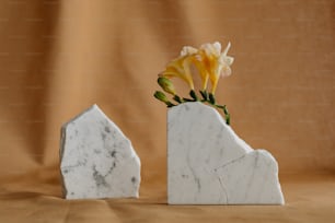 a white marble vase with a yellow flower in it