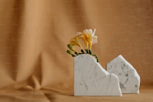 a white marble vase with a yellow flower in it