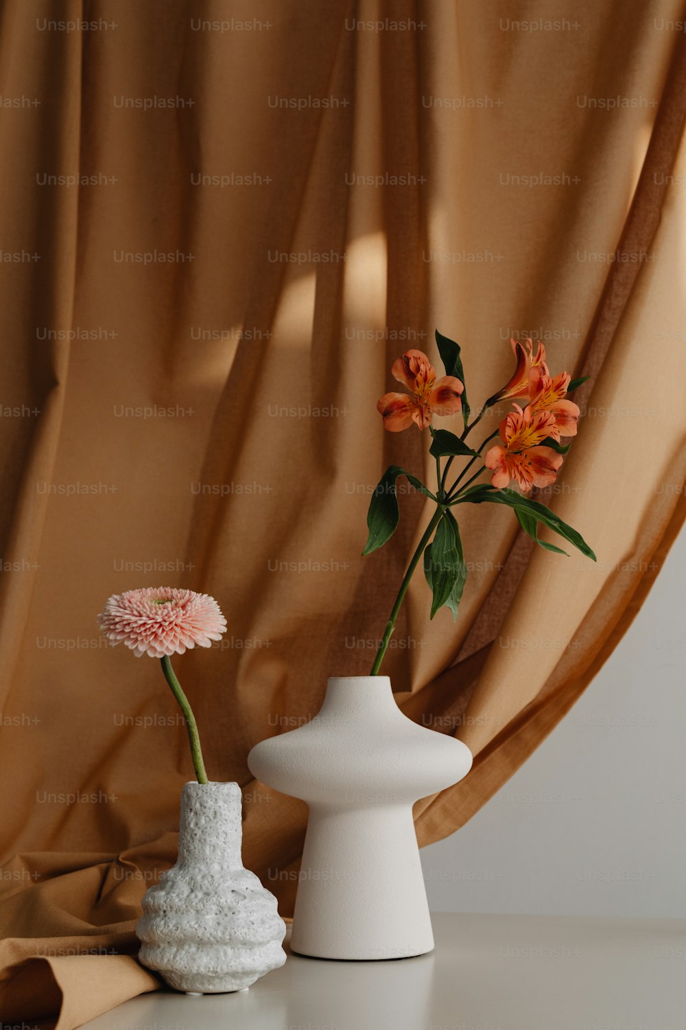 a white vase with a pink flower in it