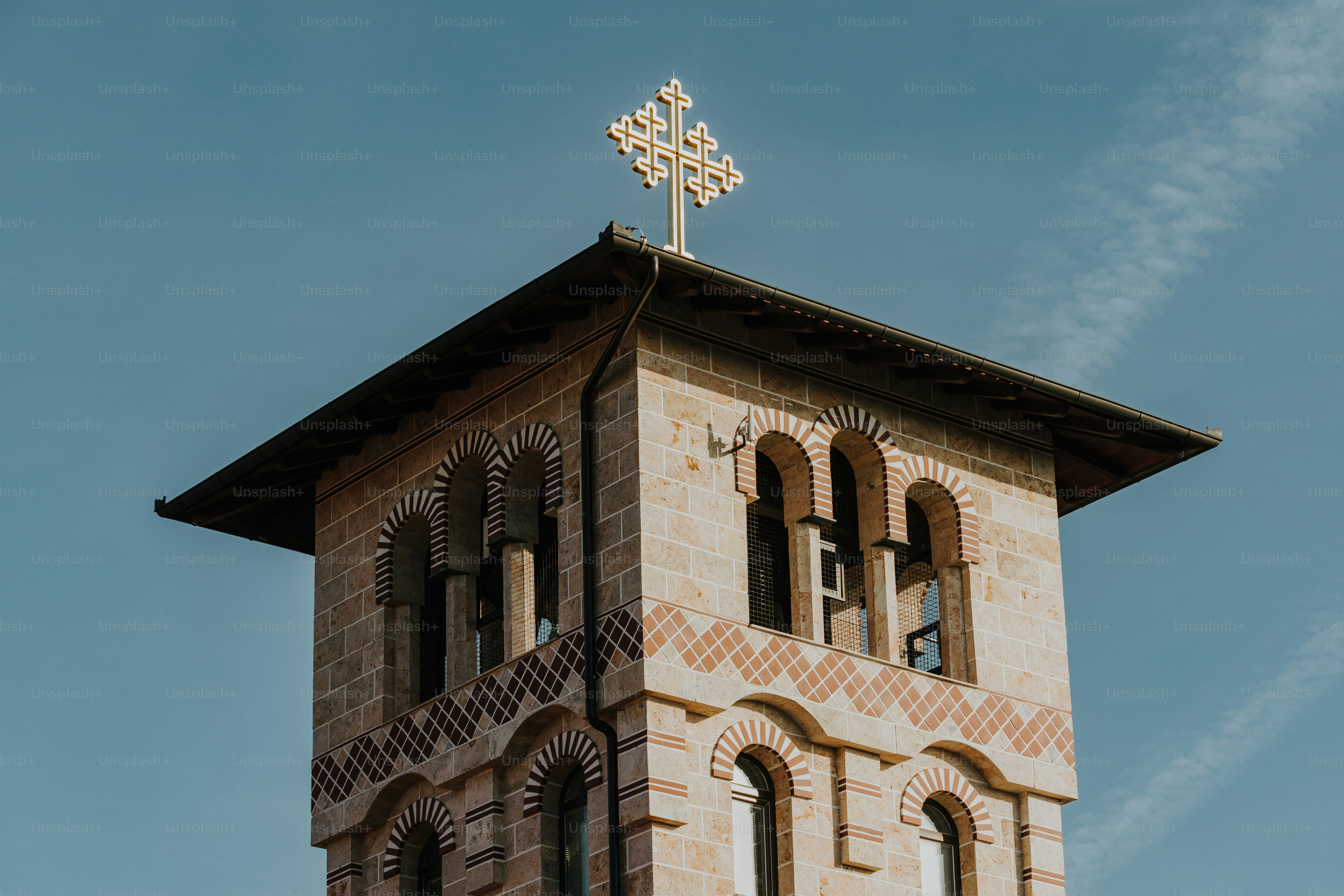 a tall brick clock tower with a cross on top
