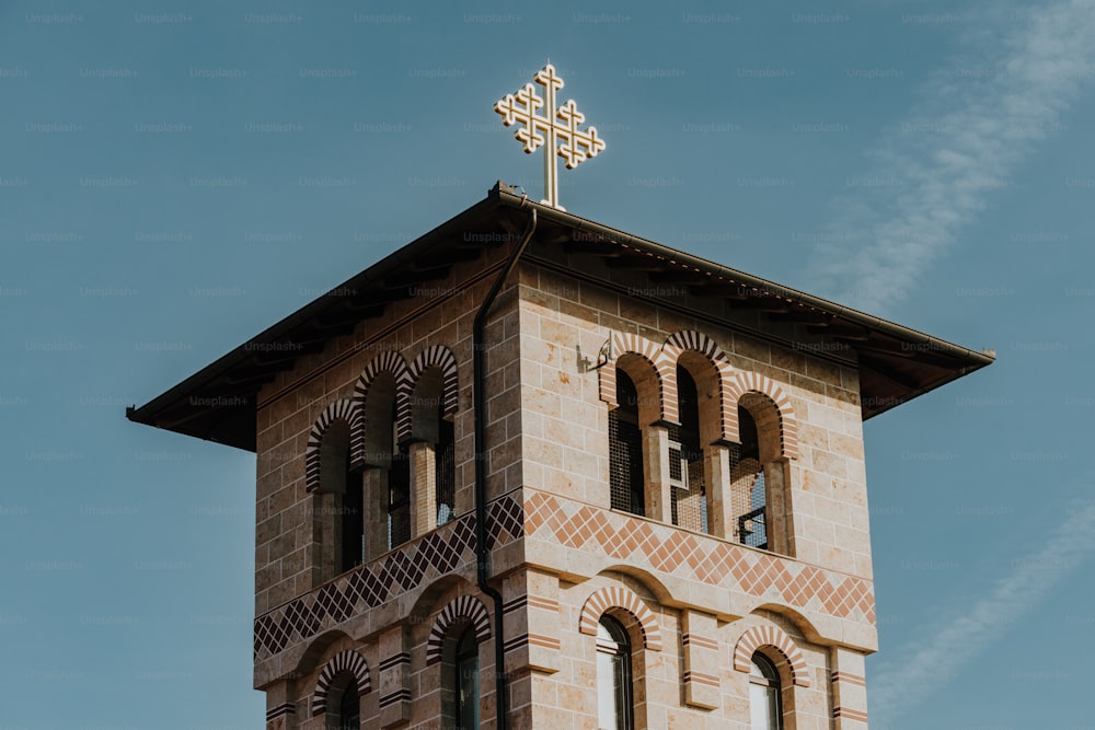 ein hoher gemauerter Glockenturm mit einem Kreuz auf der Spitze